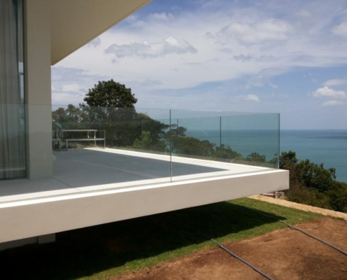 frameless-glass-balustrade-dividing-coastal-views Premium frameless glass balustrade dividing the coastal landscape from the sea, enhancing architectural aesthetics.