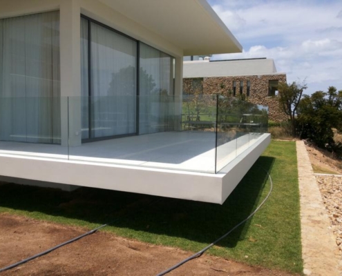 glass-balustrade-modern-balcony-safety-railing Minimalist balcony edge with a frameless glass balustrade providing safety and an unobstructed oceanfront panorama.