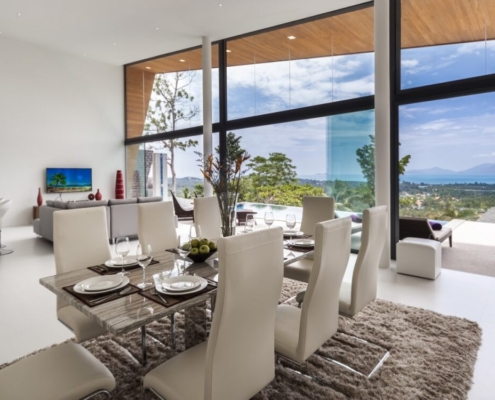 luxury-villa-glass-sliding-doors-sf20 Elegant dining area with Sunflex SF 20 frameless sliding doors and tropical garden view