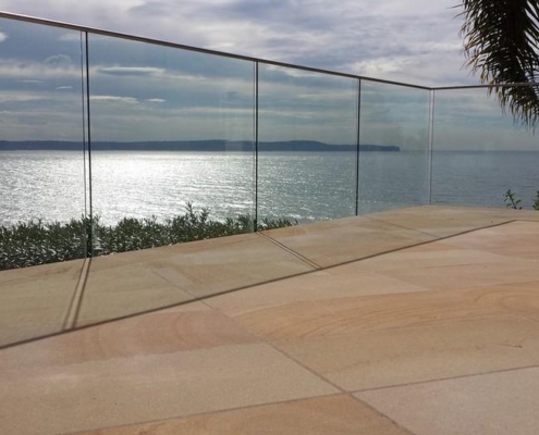 modern-ocean-view-terrace-glass-balustrade Modern minimalist home with a frameless glass balustrade on an ocean-view terrace at sunset.