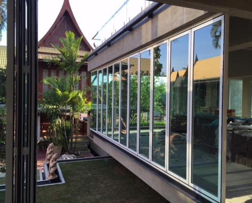 Modern SF 45 folding sliding doors seamlessly integrated into a traditional wooden Thai house.