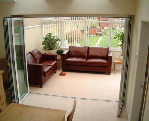 Residential living room looking out to a garden through fully open SF 45 bifold patio doors.