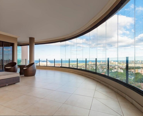 sf25-curved-balcony-glazing-panoramic-view Curved balcony featuring a frameless SF 25 system for uninterrupted panoramic views.