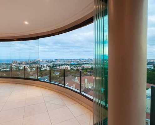 sf25-curved-glass-wall-parked-panels Frameless glass panels of the SF 25 system parked against a pillar on a curved balcony.