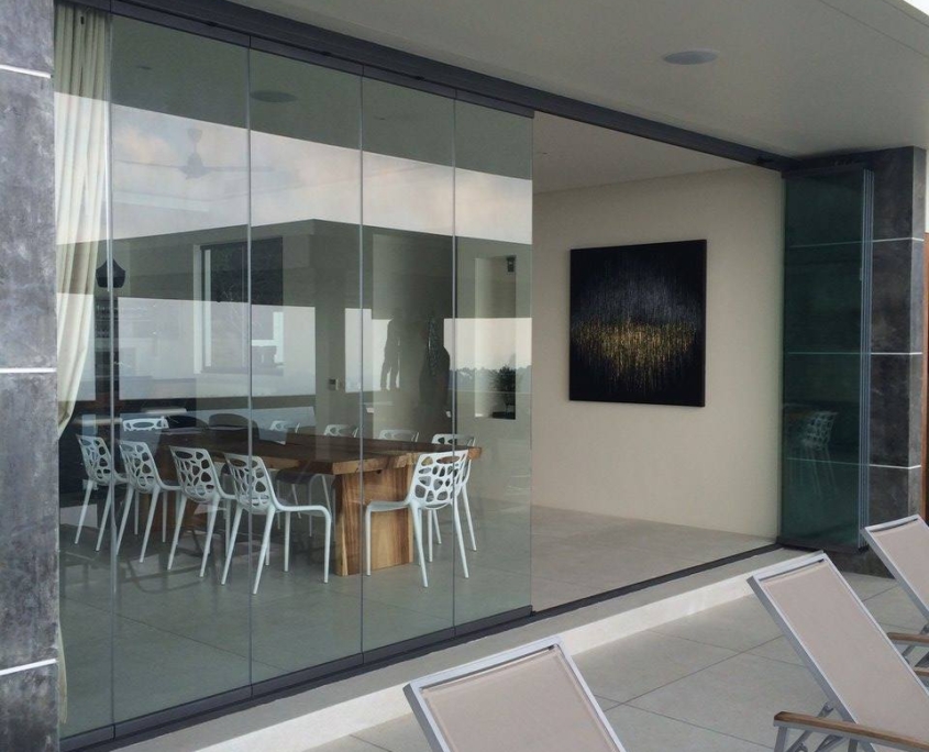 sf25-dining-area-frameless-glass-enclosure Minimalist dining area enclosed by an SF 25 all-glass system overlooking the pool.