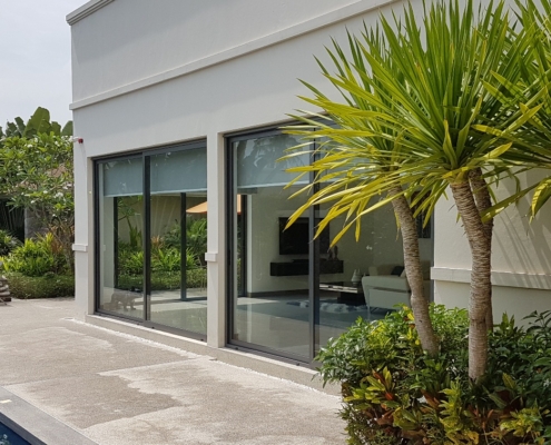 sf42-glass-sliding-system-white-building-facade SF 42 glass sliding system integrated into a modern white building facade with tropical plants.