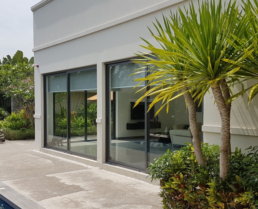 sf42-glass-sliding-system-white-building-facade SF 42 glass sliding system integrated into a modern white building facade with tropical plants.