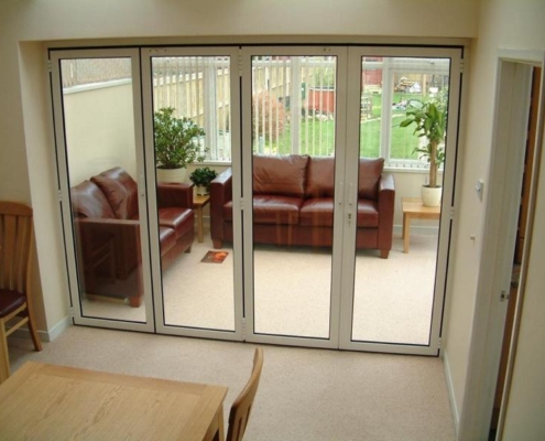 Fully closed, storm-proof aluminum folding patio enclosure by Sunflex protecting a residential interior.