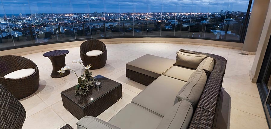 Luxury penthouse interior in Thailand featuring a Sunflex SF 25 frameless curved glass wall with a panoramic city view.