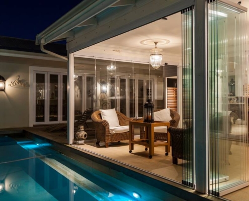 sunflex-sf25-evening-villa-interior-poolside Warmly lit villa interior with SF 25 slide and turn doors leading to a private pool.