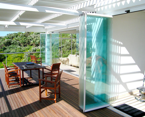 sunflex-sf25-slide-turn-parked-panels-deck SUNFLEX SF 25 frameless glass panels parked at the side on an outdoor terrace.