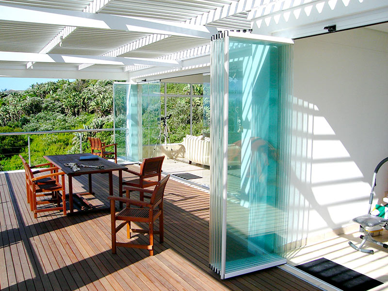 sunflex-sf25-slide-turn-parked-panels-deck SUNFLEX SF 25 frameless glass panels parked at the side on an outdoor terrace.