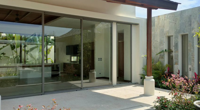 sunflex-sf26-aluminum-sliding-doors-modern-living-thailand Interior view of a modern living area with Sunflex SF 26 aluminum sliding doors opening to a tropical garden in Thailand.