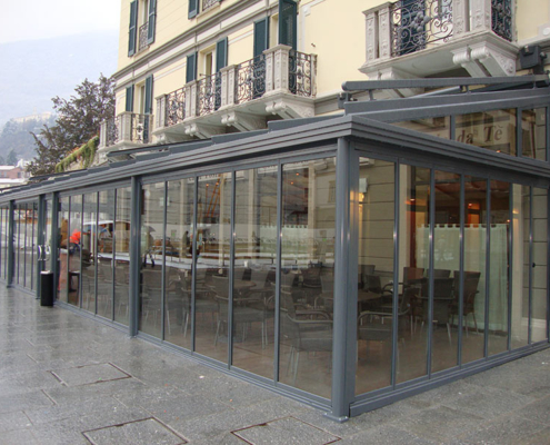 Weatherproof framed SF 25 slide and turn system protecting a restaurant terrace from rain.